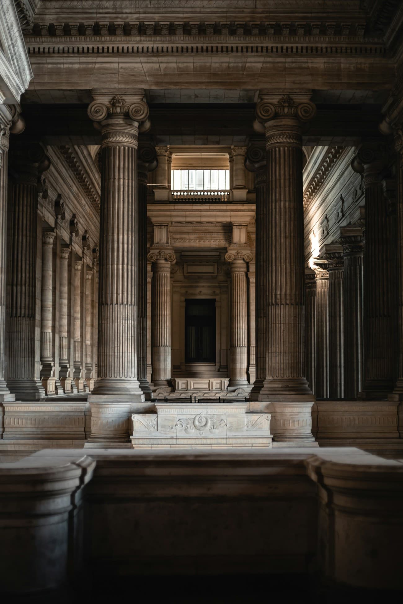 Interior en penumbra de un palacio de justicia, con columnas de piedra y una escalinata al fondo